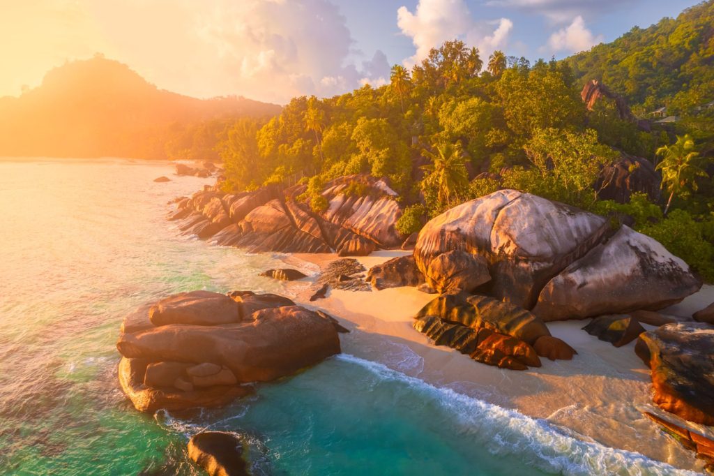 Sunset over Baie Lazare, showcasing rocky coastline and lush greenery, Seychelles