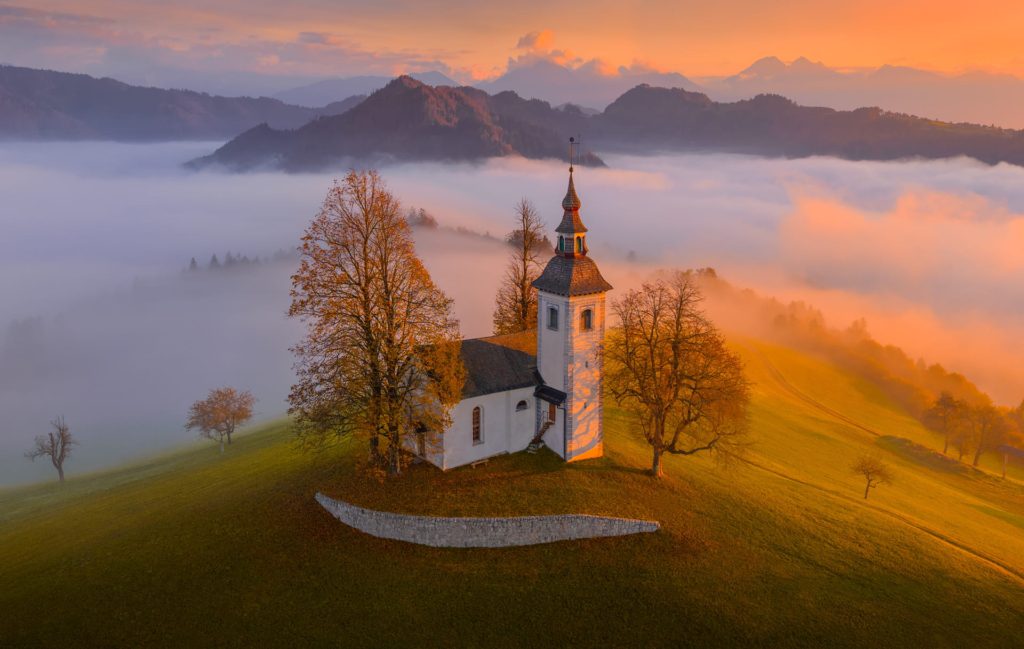 Cerkev Sv Tomaz surrounded by mist at sunrise, Slovenia