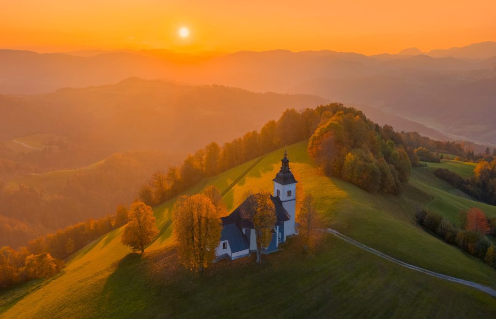 Cerkev Žalostne Matere Božje at sunset in Slovenia's hills