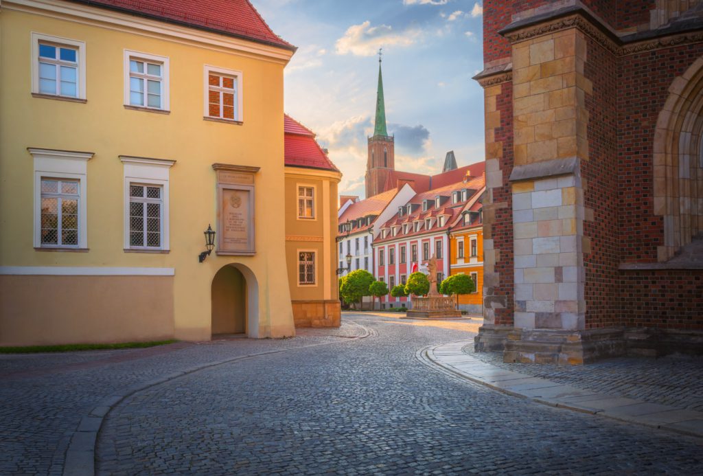 Charming cobbled street in Wrocław, Poland, with historic buildings and a church spire