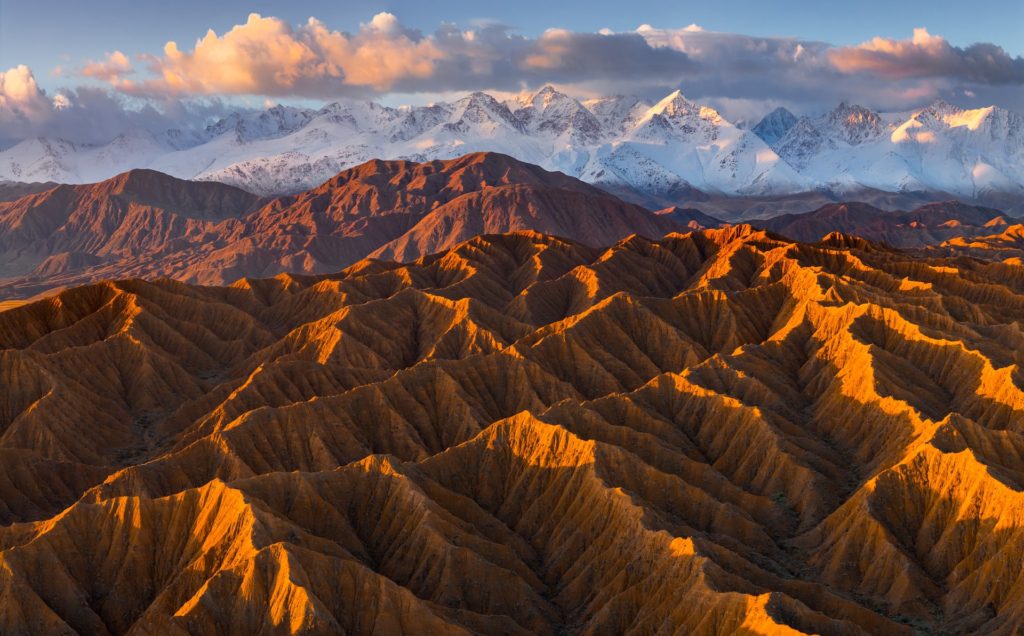 Sunrise illuminating rugged valleys and snow-capped mountains in Kyrgyzstan