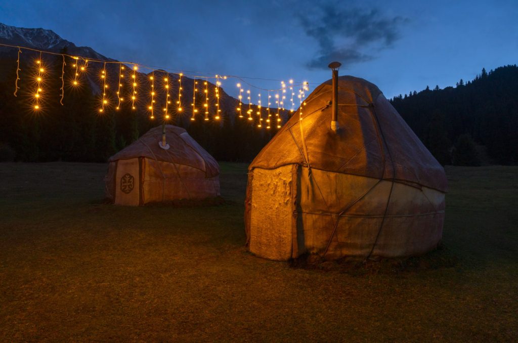 Yurts illuminated by string lights in Kyrgyzstan's mountainous landscape