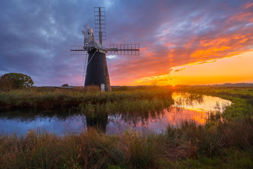 Muttons Mill windmill at sunset reflecting in water, Norfolk, England