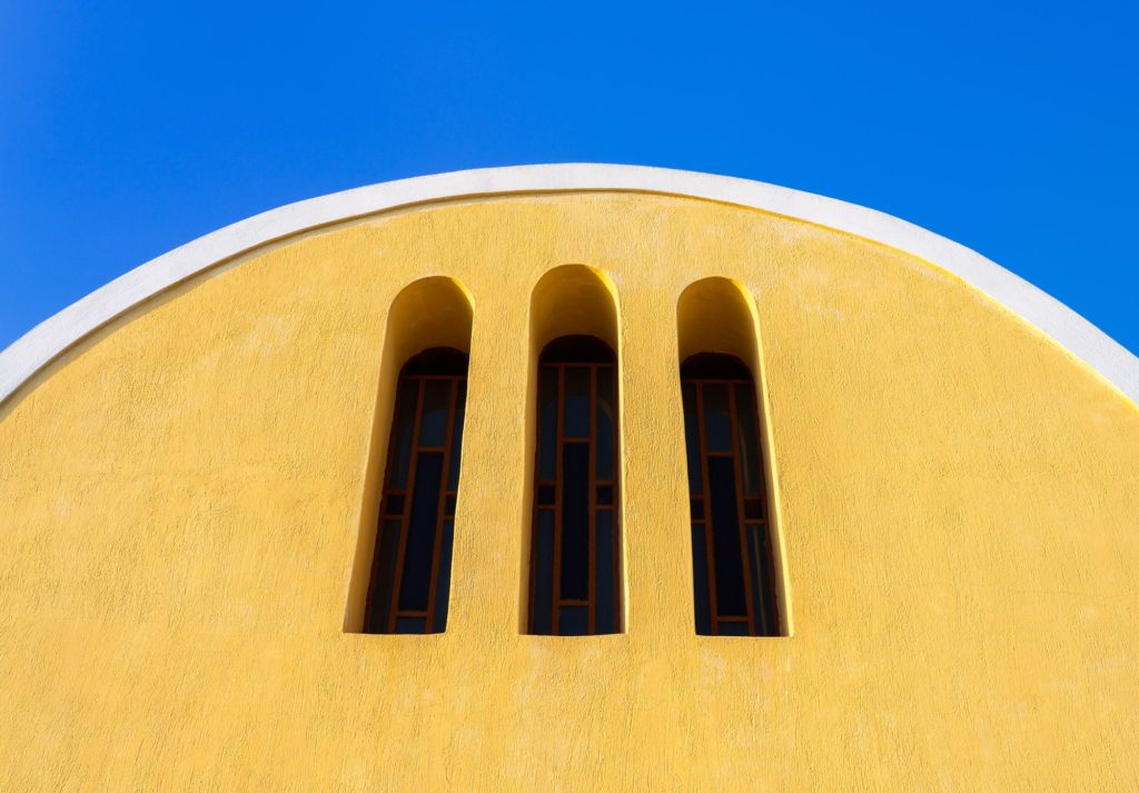 Yellow church facade with three arched windows, Oia, Santorini, Greece