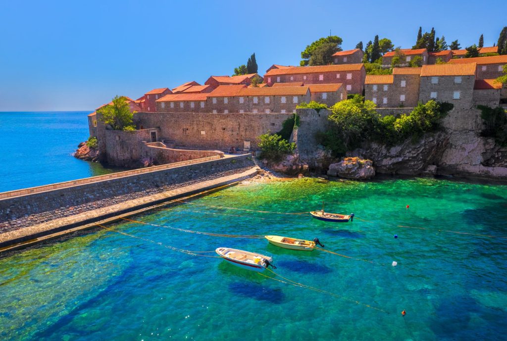 Sveti Stefan's coastal view with boats and clear blue sky, Montenegro