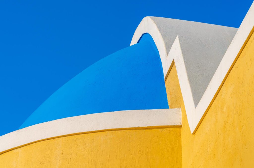 Bright blue dome and yellow wall in Santorini, Greece
