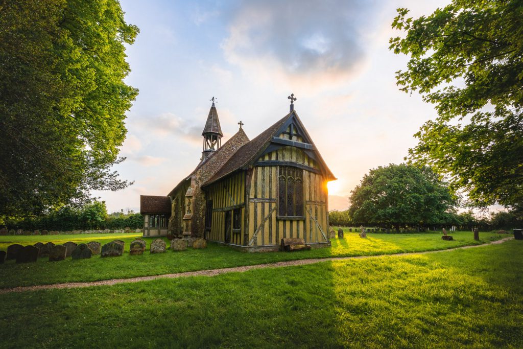All Saints Church in Crowfield, Suffolk, surrounded by gravestones and trees