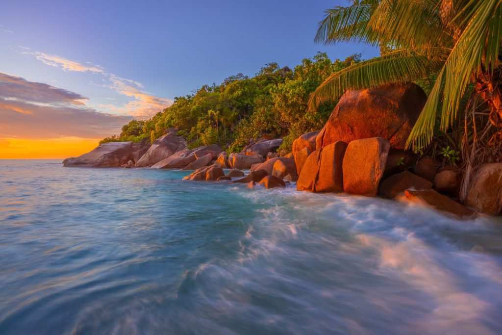 Anse Lazio beach at sunset, Seychelles with rocky shoreline and palm trees