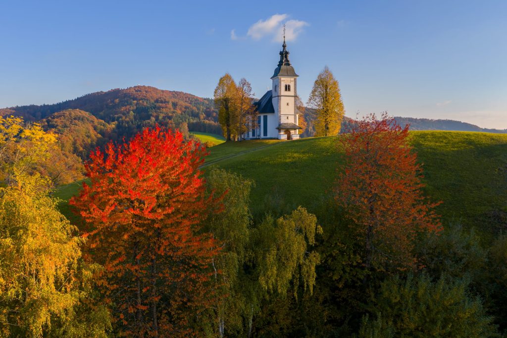 Autumn landscape featuring a church and vibrant foliage in Slovenia