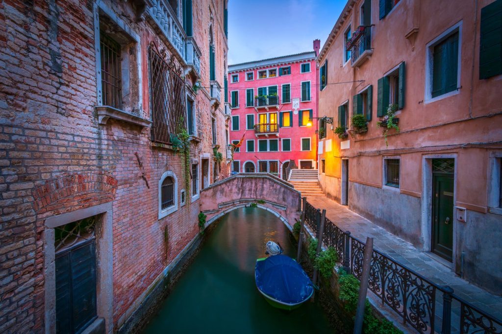 Venice canal at blue hour with colourful buildings and a boat