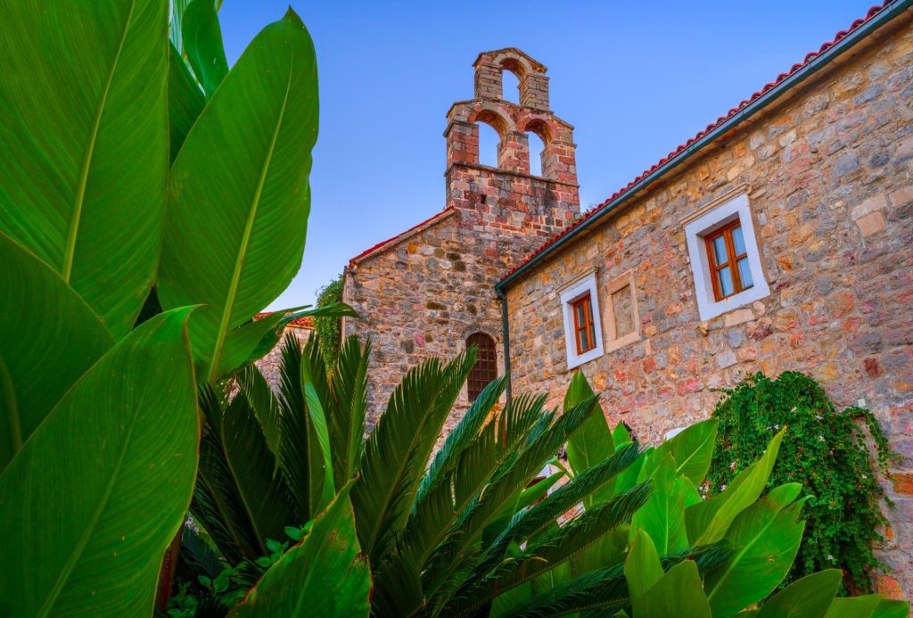 Morning light illuminates stone buildings and lush greenery in Budva, Montenegro