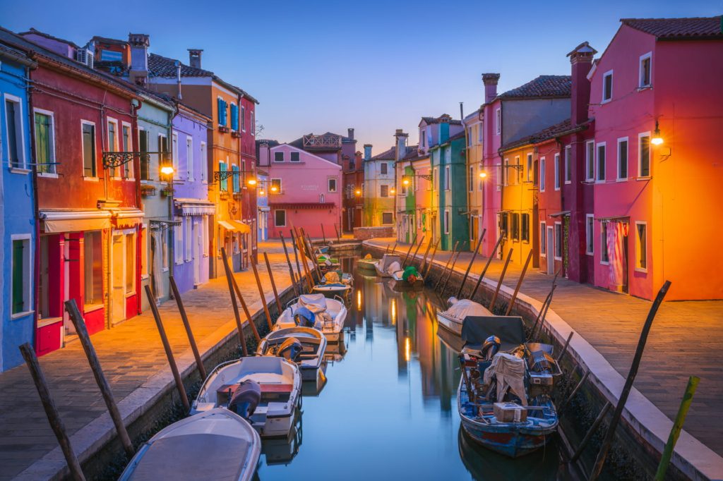 Vibrant houses lining a canal at blue hour in Burano, Venice, Italy