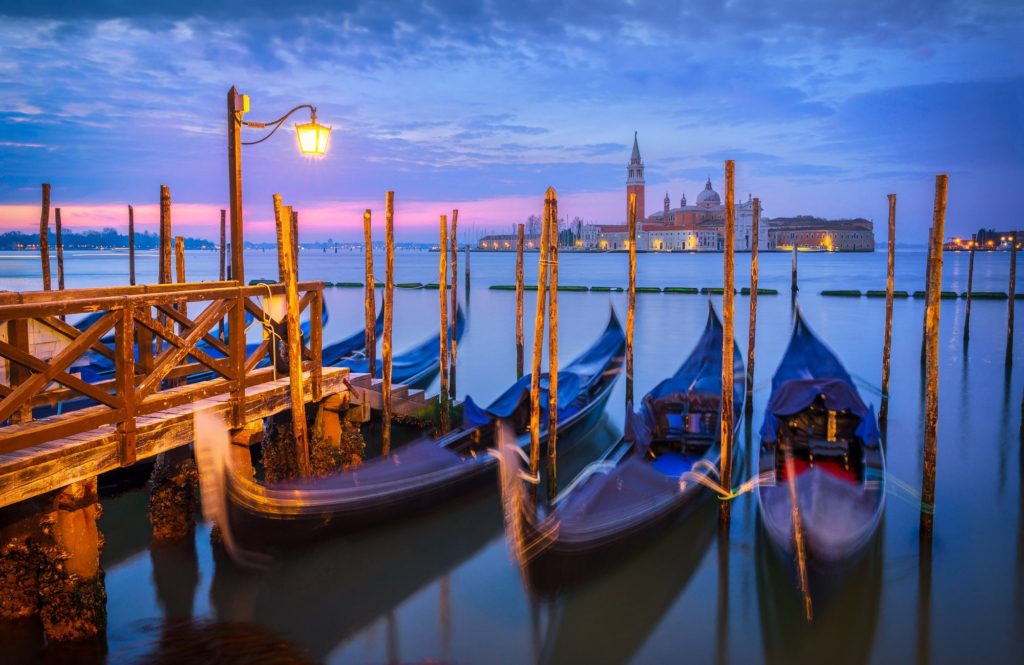 Gondolas at sunrise near wooden pier, Venice, Italy