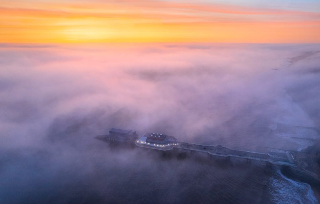 Cromer Pier emerging from morning mist at sunrise, Norfolk, England