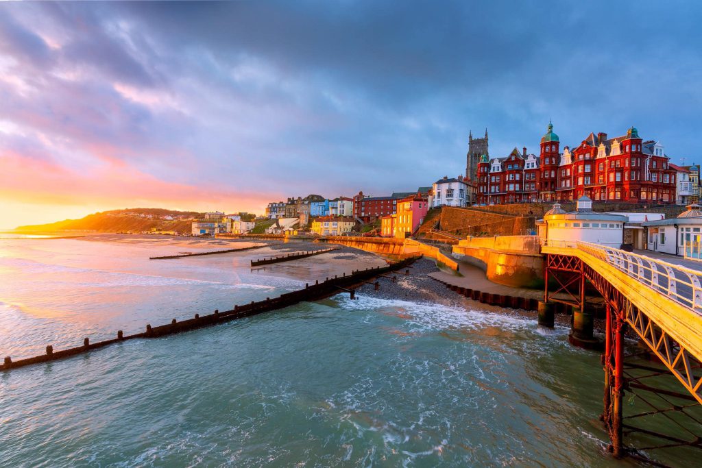 Sunrise over Cromer Pier and colourful buildings, Norfolk, England