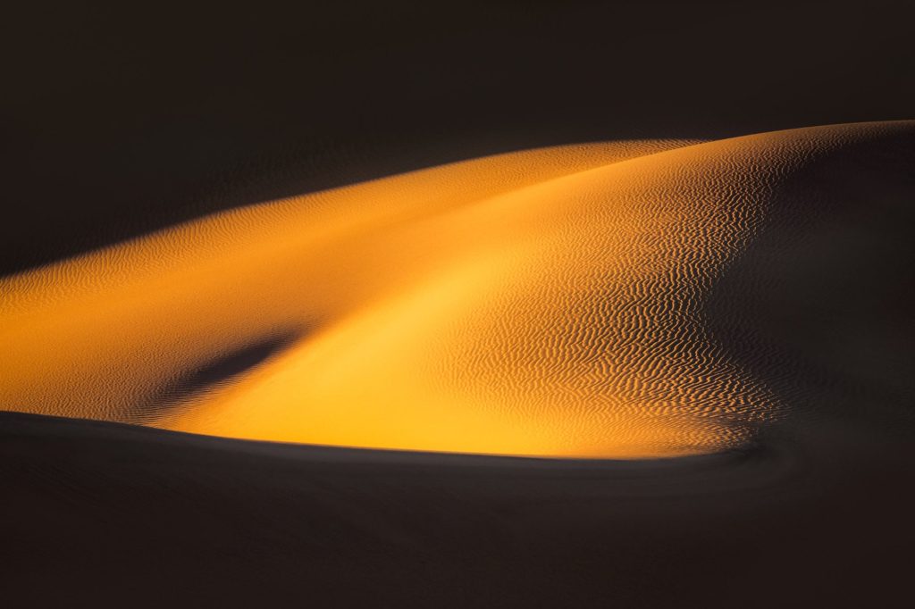 Golden light illuminating sand dunes in Death Valley, USA