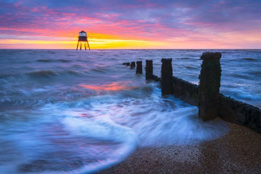 Dovercourt lighthouse at sunrise with vibrant sky and waves
