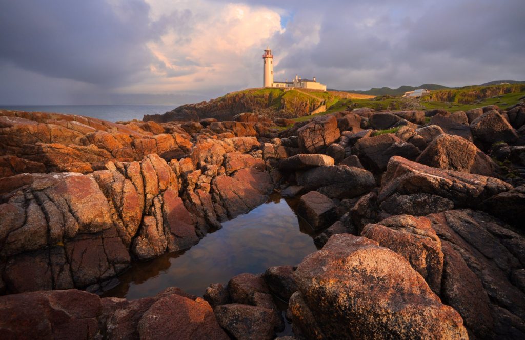 Fanad Lighthouse beside a rock pool under stormy skies, Ireland