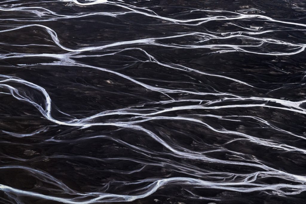 Braided glacial river flowing over dark terrain in Iceland