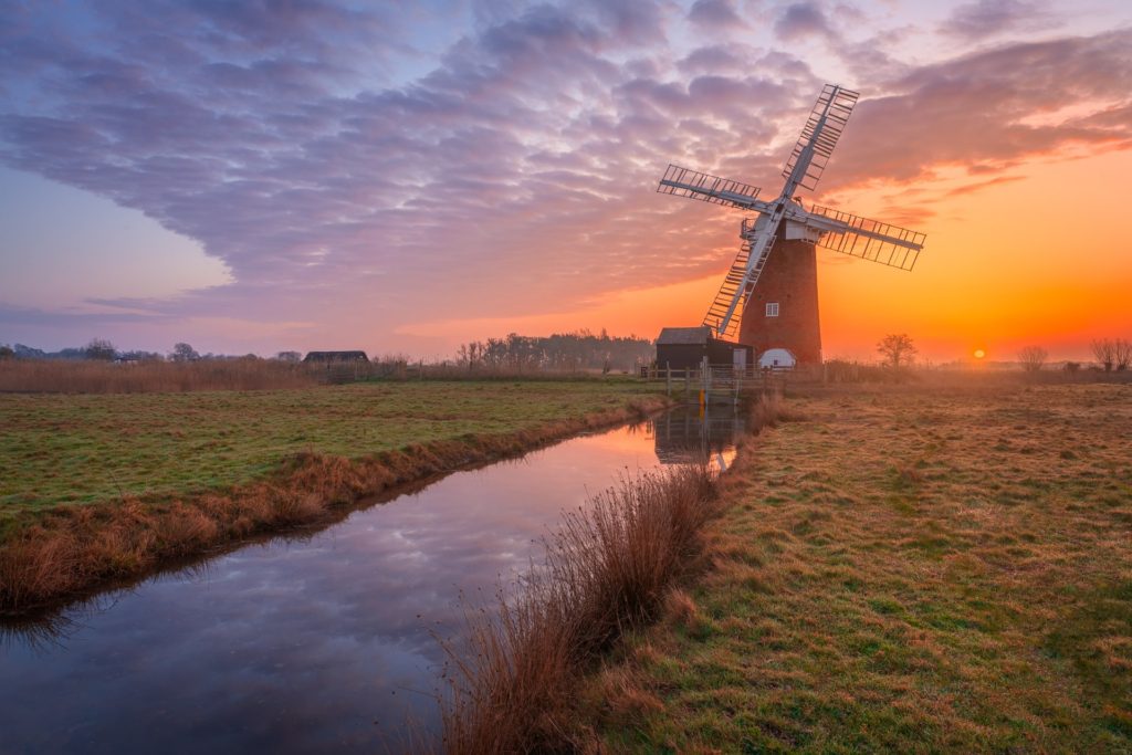 Spring sunrise over Horsey windmill and reflective water, Norfolk, England