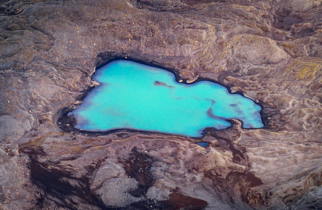 Turquoise glacier pool surrounded by dark volcanic terrain, Iceland