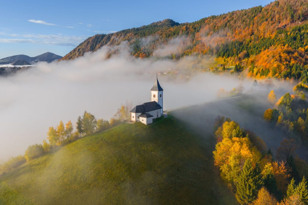 Jaminik church surrounded by autumn foliage and mist, Slovenia