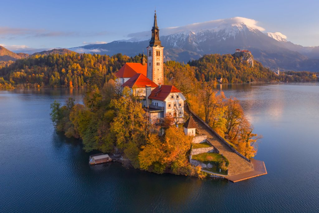 Church on island in Lake Bled, Slovenia, surrounded by autumn foliage