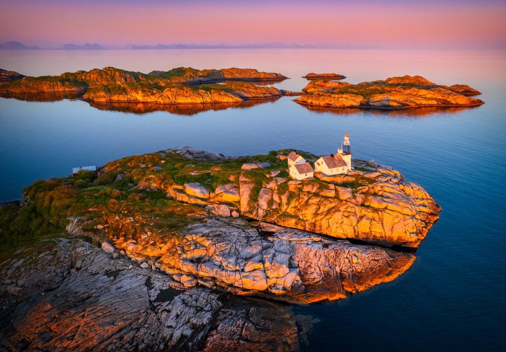 Midnight sun illuminating a lighthouse on rocky islands, Lofoten, Norway