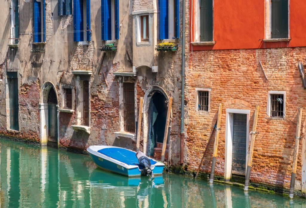 Lone blue boat moored beside colourful Venetian buildings in Venice, Italy