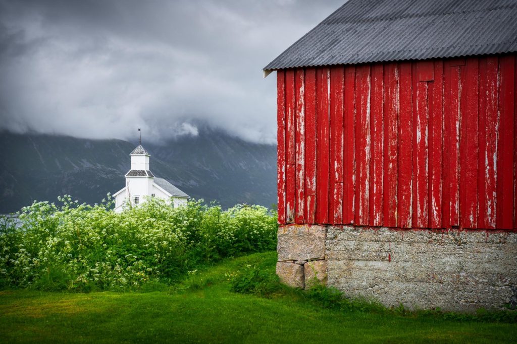 Red barn and white church amidst moody weather in Lofoten, Norway