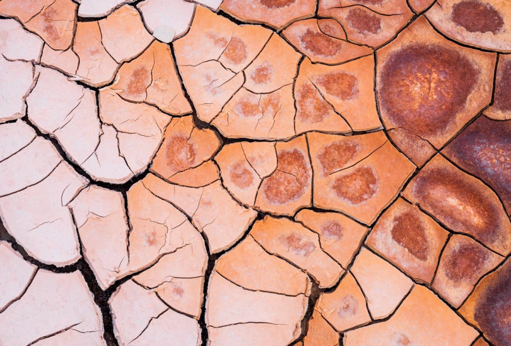 Multi-coloured mud cracks in a dry landscape