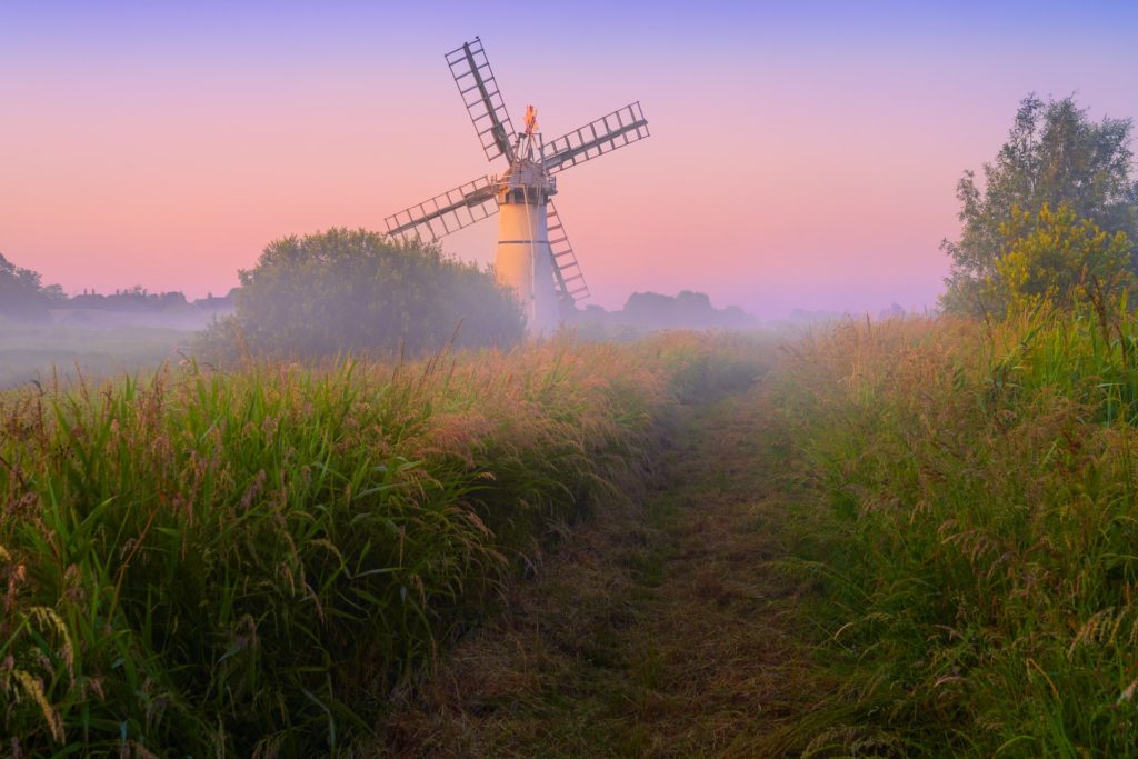 Thurne Mill surrounded by misty fields in Norfolk, England