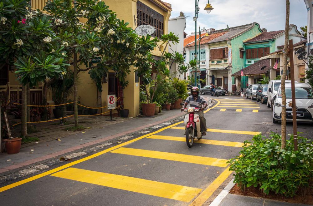 Street in Penange, Malaysia, with man riding a motorbike