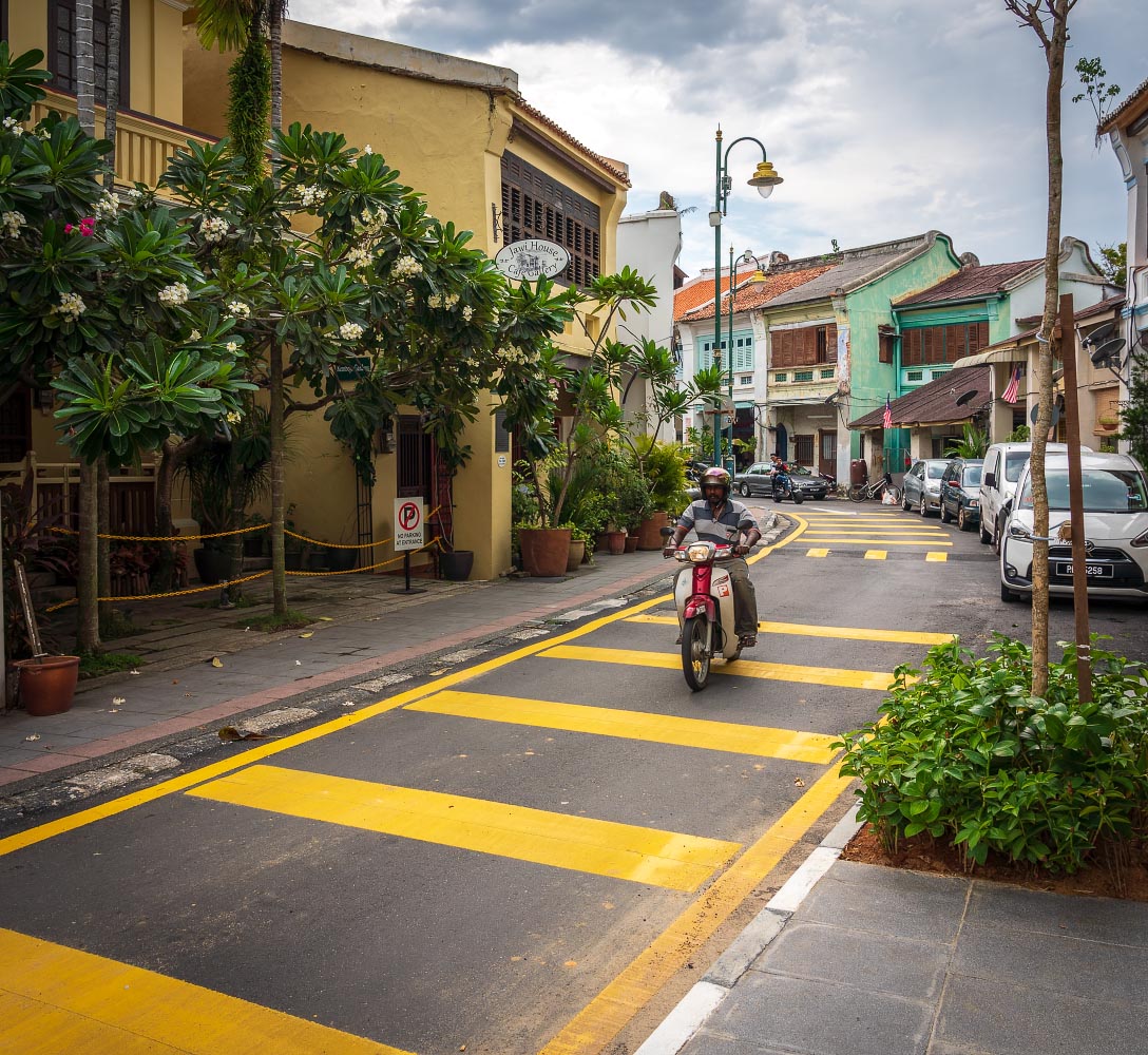 Street in Penange, Malaysia, with man riding a motorbike