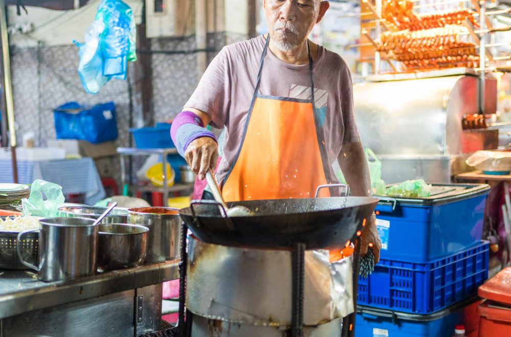 Chef on a food street market in Penange, Malaysia, cooking