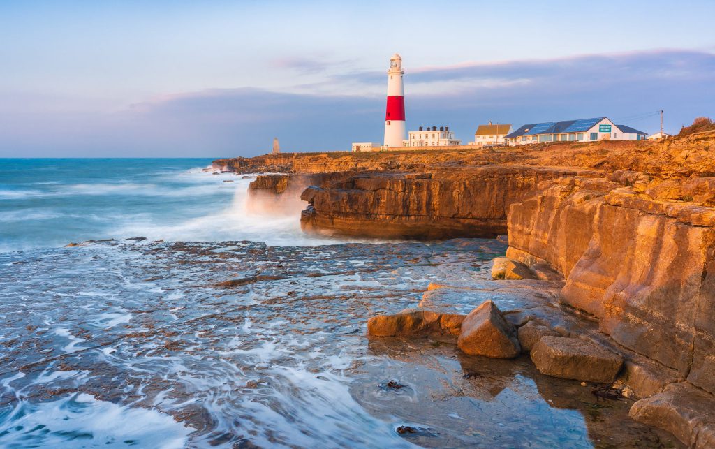 Portland Bill lighthouse at sunrise, Dorset, England with rocky coastline