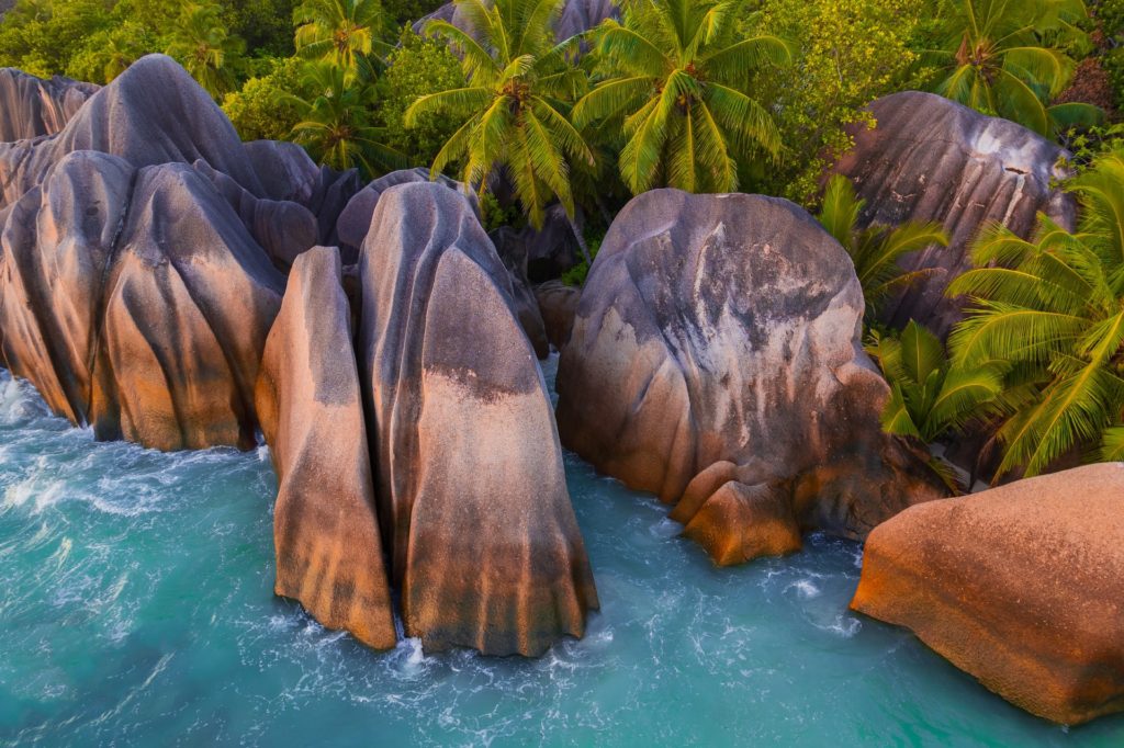 Granite boulders surrounded by turquoise water and palm trees, Seychelles