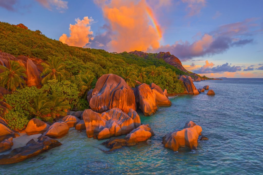 Rainbow arching over rocky coastline at La Digue, Seychelles