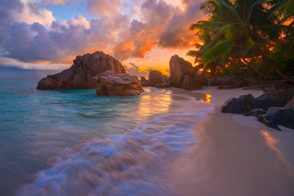 Sunrise over La Digue beach with rocks and palm trees, Seychelles