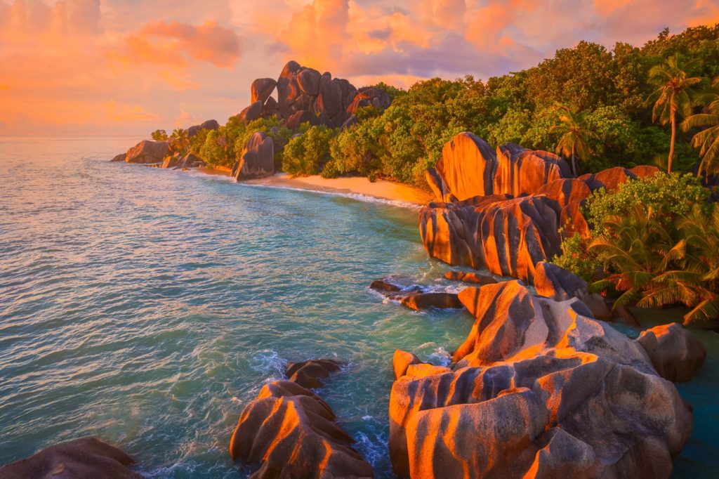 Tropical beach at sunset with rocky coastline, Seychelles