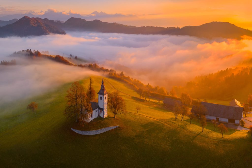 Hilltop church surrounded by mist at sunrise, Slovenia