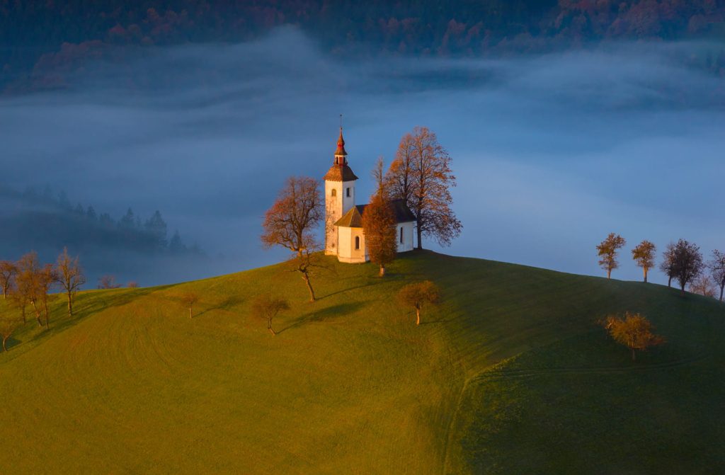 Morning mist envelops a church on a hill in Slovenia