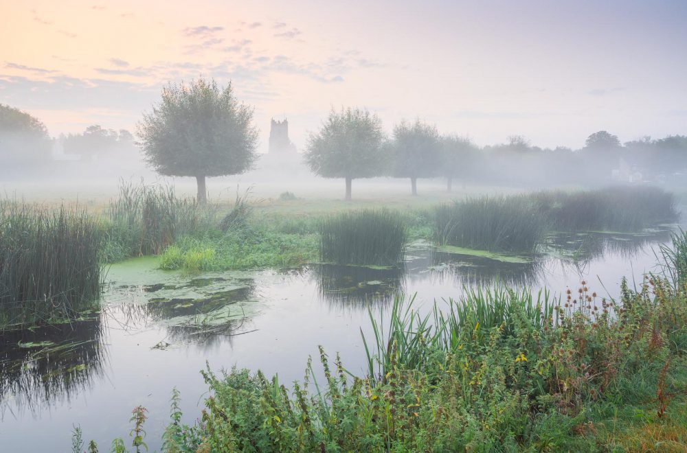 Sudbury water meadows with mist and fog with the church in the distance