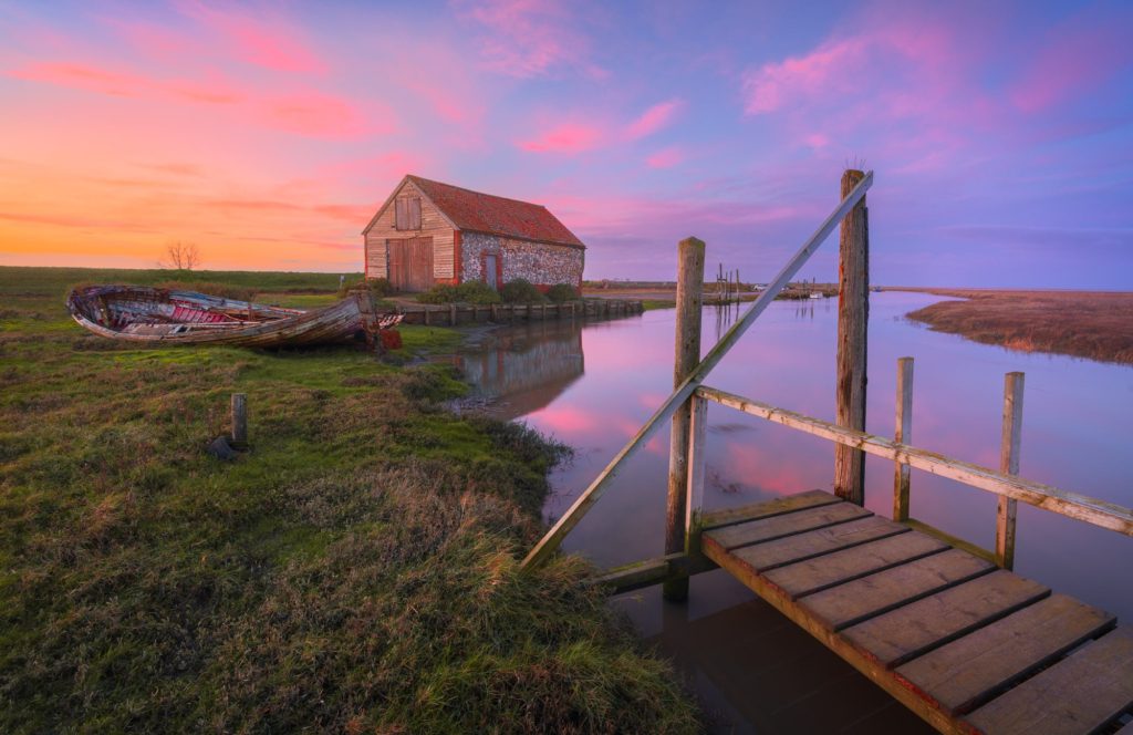 Thornham sunset with a boathouse and moored boats, Norfolk, England