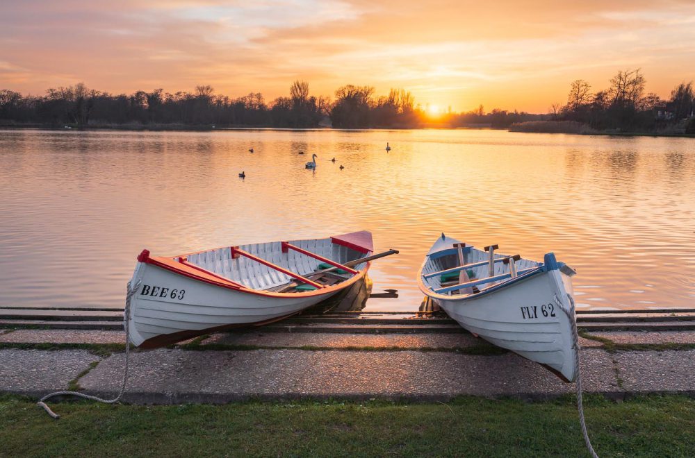 Rowing boats at Thorpeness Meare, Aldeburgh with golden setting sun