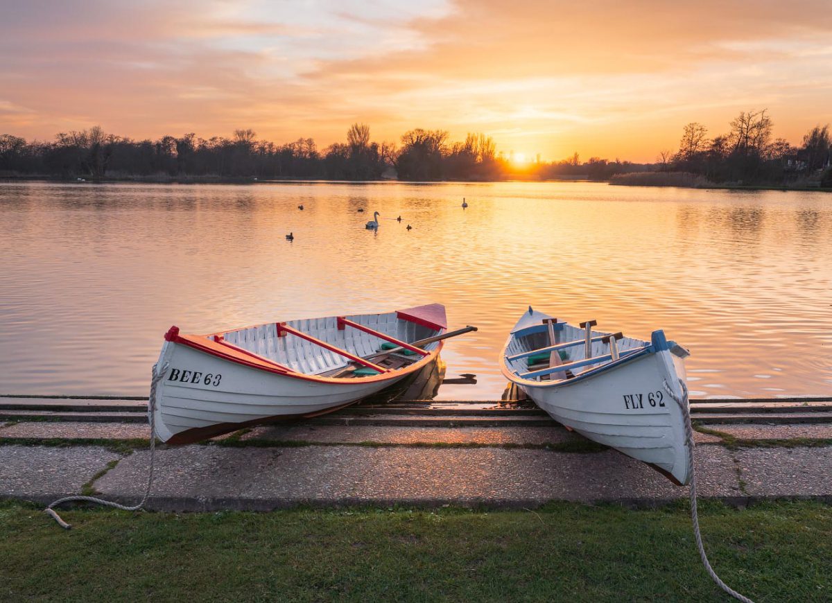 Rowing boats at Thorpeness Meare, Aldeburgh with golden setting sun