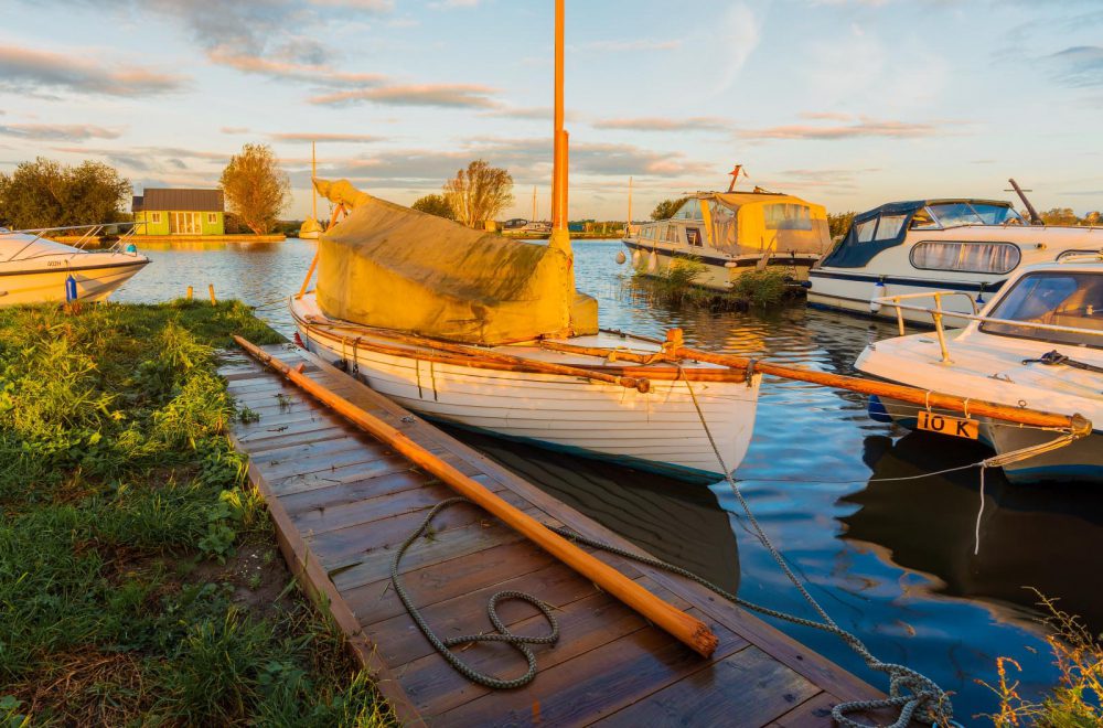 Moored boat with golden sunlight at Thurne Mill in Norfolk