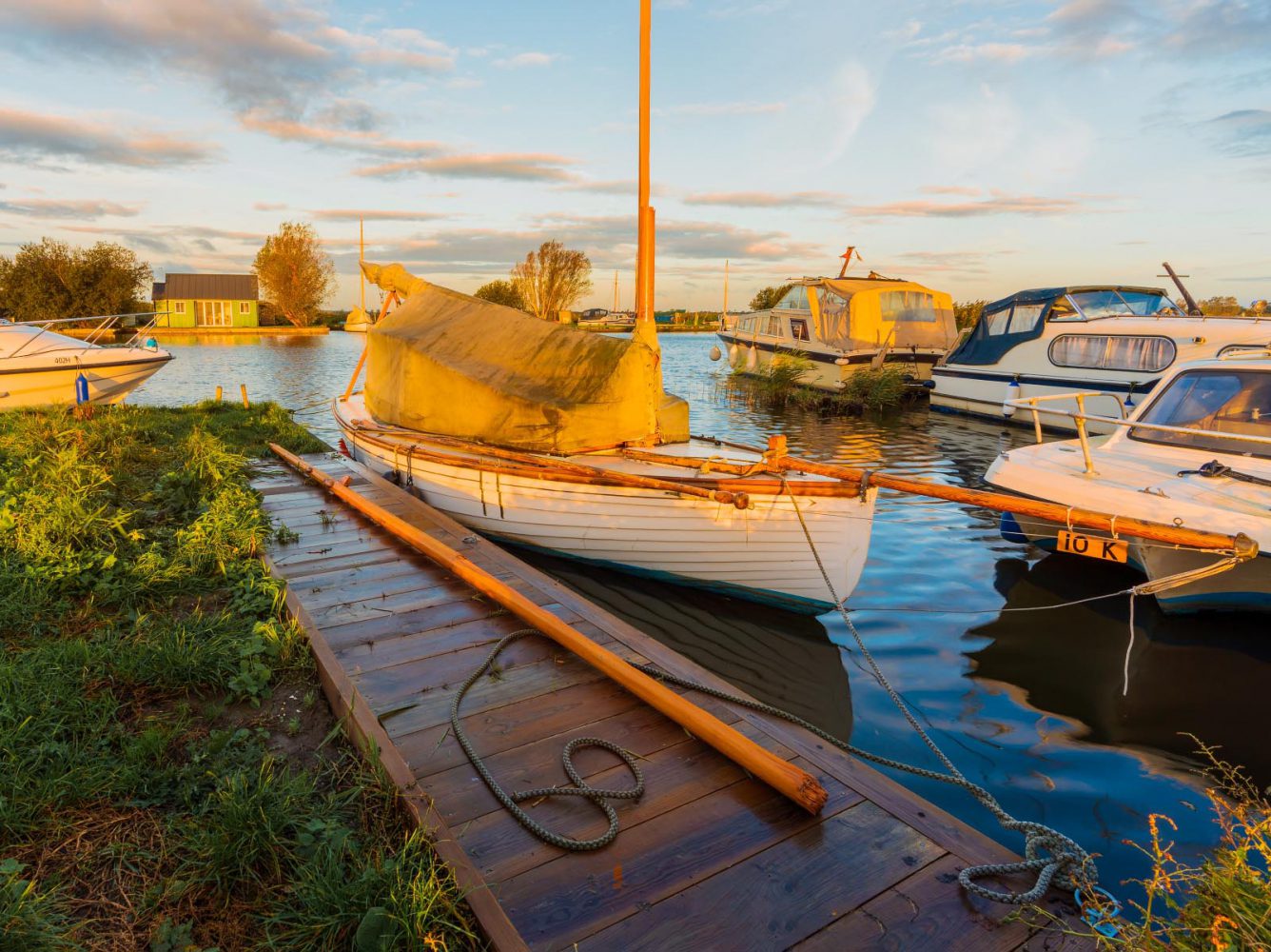 Moored boat with golden sunlight at Thurne Mill in Norfolk