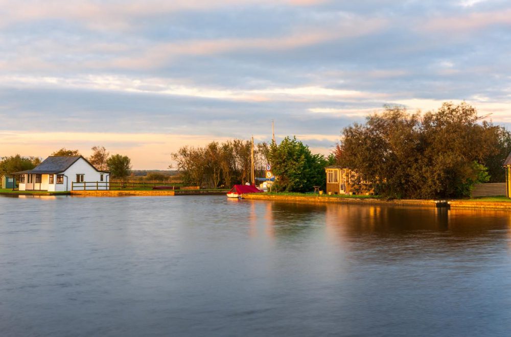 Riverside houses on the River Thurne covered in golden sunrise light