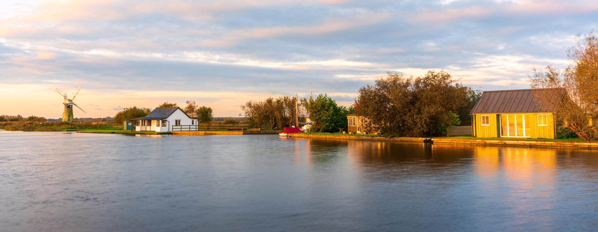 Riverside houses on the River Thurne covered in golden sunrise light